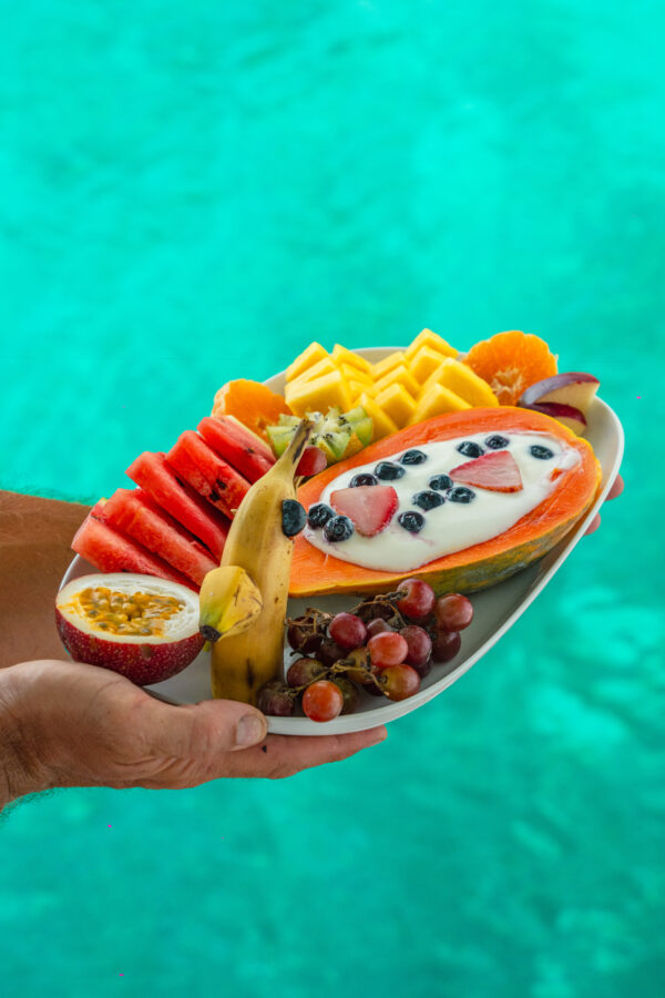 “Tropical breakfast of fresh fruits and yogurt served on a sailing yacht in San Blas, Panama with clear turquoise water in the background”