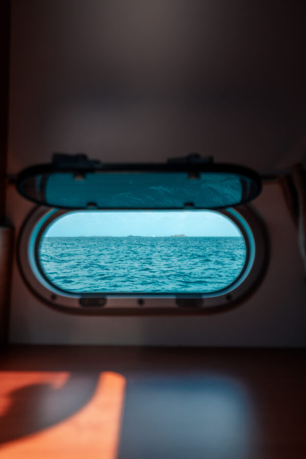 View of the Caribbean Sea through a yacht cabin window during a luxury sailing charter in San Blas, Panama.