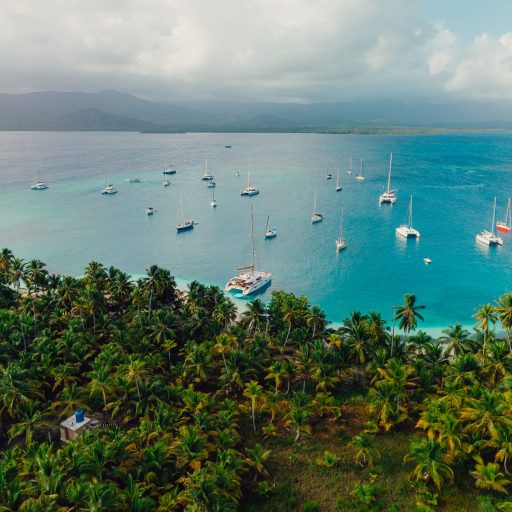 aerial-view-sailboats-san-blas-panama-luxury-sailing.jpg Aerial photo of multiple sailboats anchored off the lush green islands of San Blas, Panama, surrounded by turquoise Caribbean waters.
