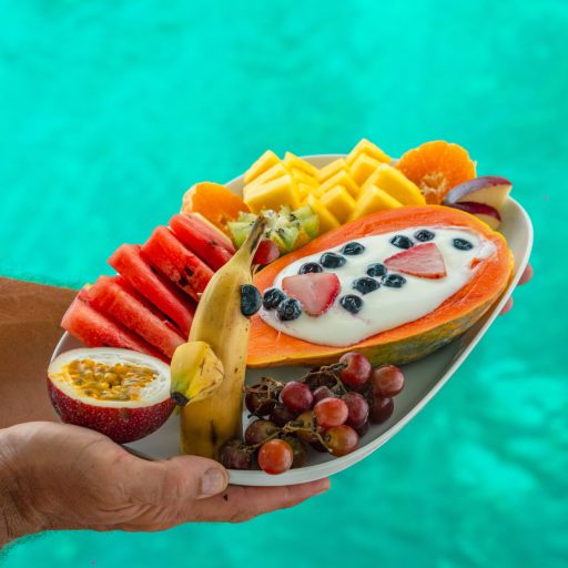 Suxury-sailing-san-blas-panama-tropical-breakfast “Tropical breakfast of fresh fruits and yogurt served on a sailing yacht in San Blas, Panama with clear turquoise water in the background”